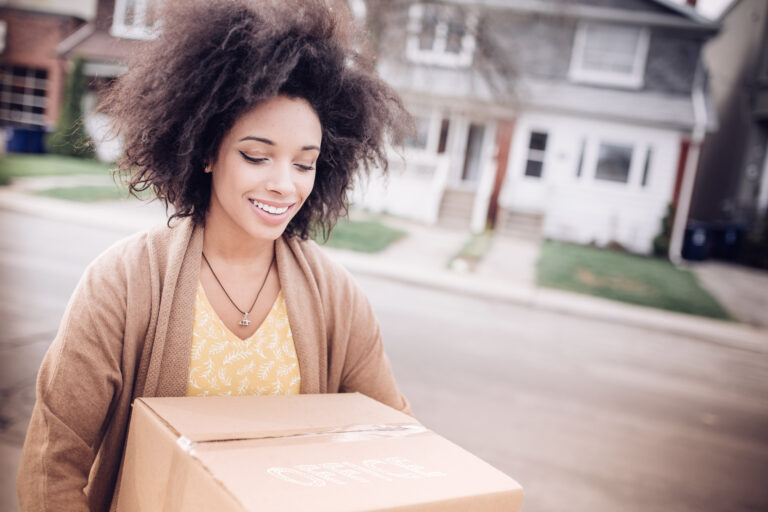 Jeune femme heureuse transportant une boîte de déménagement vers sa nouvelle maison