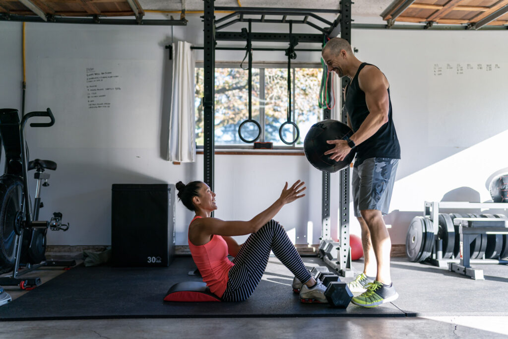 Un couple s'entraîne ensemble dans la salle de sport qu'ils ont aménagée dans le garage de leur maison.