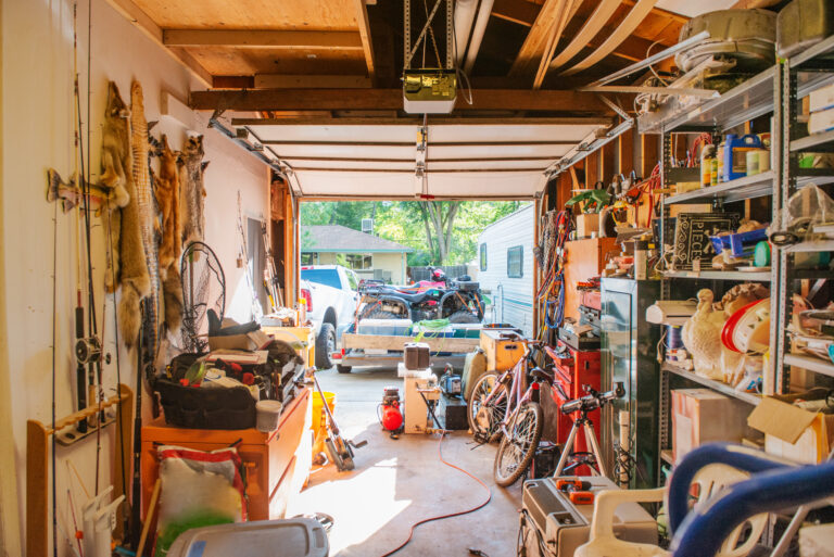 Un garage dont les étagères sont remplies d'objets entreposés à la maison, notamment des outils, des produits d'entretien, des décorations de Noël et du matériel de sport.