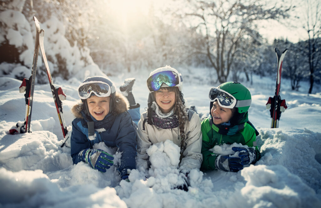 Trois jeunes skieurs riant et jouant dans la neige