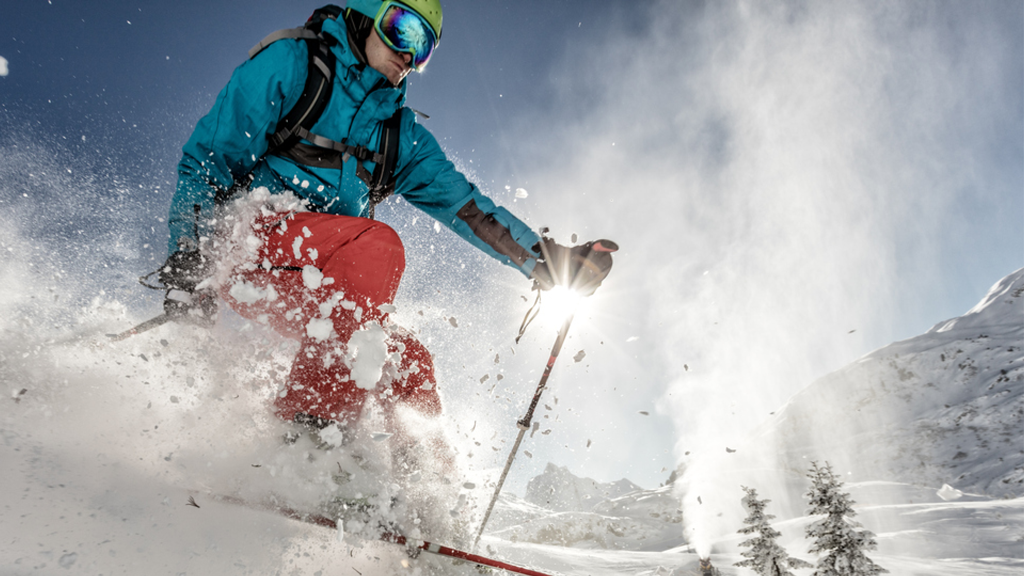 Homme dans une parka d’hiver bleue et un pantalon de neige rouge en ski alpin pendant la journée