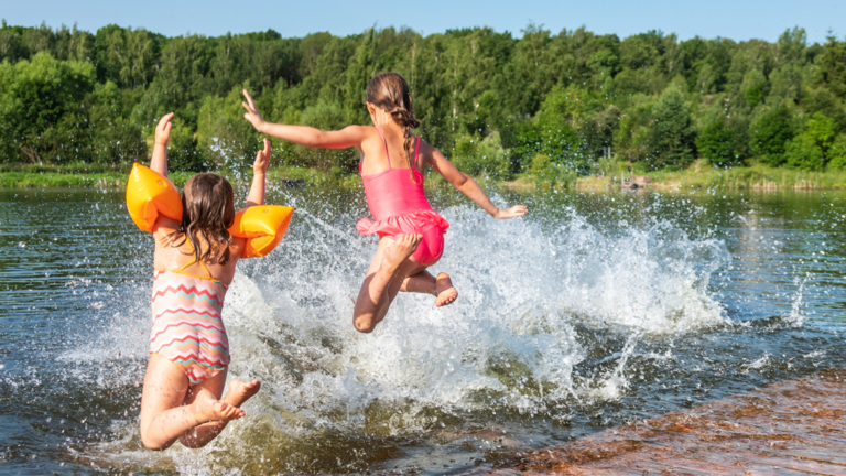 Deux enfants en maillot de bain sautant d'un quai dans le lac pendant l'été