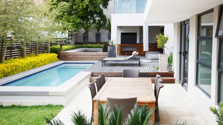 Un jardin moderne avec une piscine creusée et un patio avec des meubles