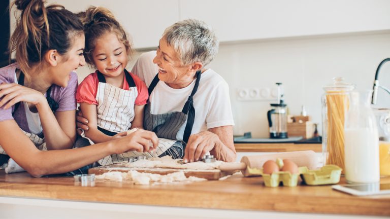 Une grand-mère, une mère et une fille cuisinent ensemble dans une cuisine.