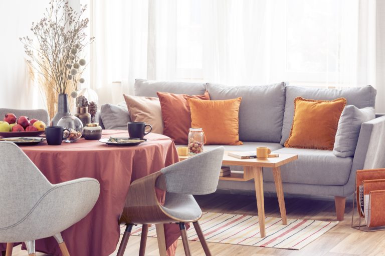 Salon moderne avec canapé gris et décor d’automne