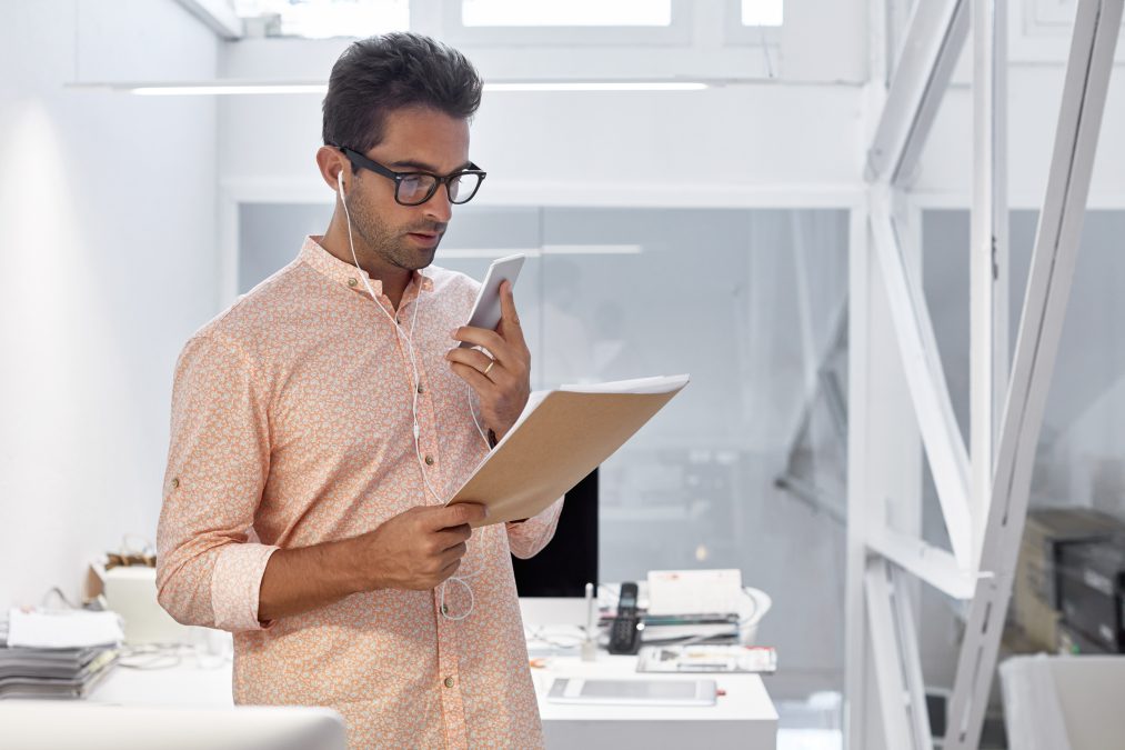 Homme d’affaires dans un bureau moderne prenant le téléphone avec un dossier dans l’autre main