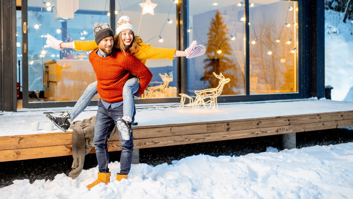 Un homme et une femme vêtus de pulls colorés jouent dans la neige.