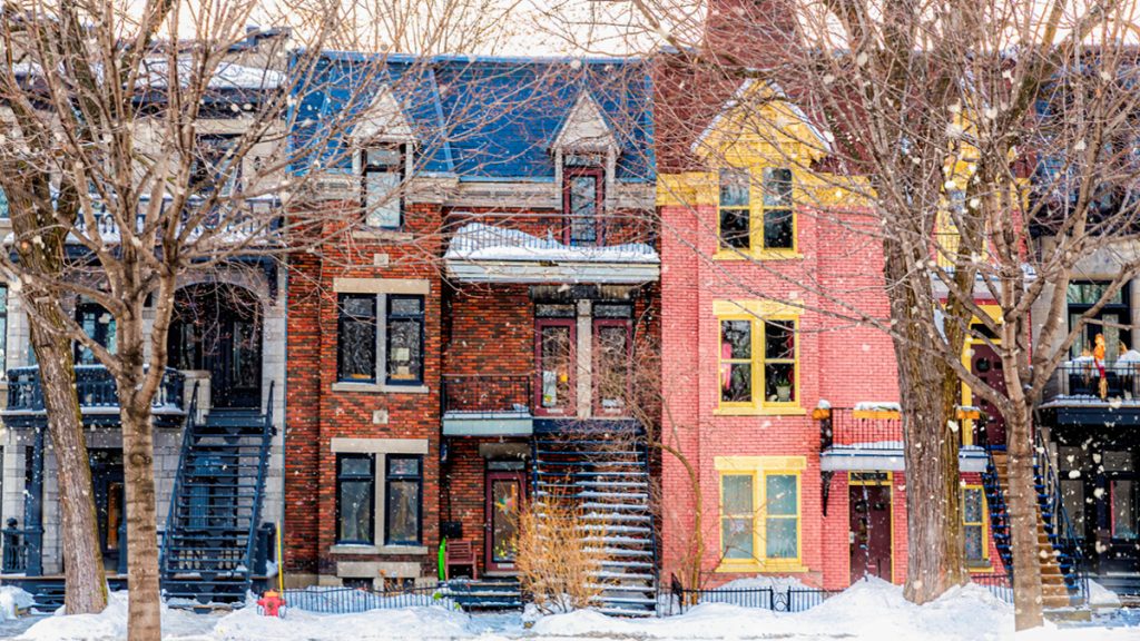 Rue d'hiver à Montréal, avec une architecture de style traditionnel, des balcons enneigés et de fortes chutes de neige.