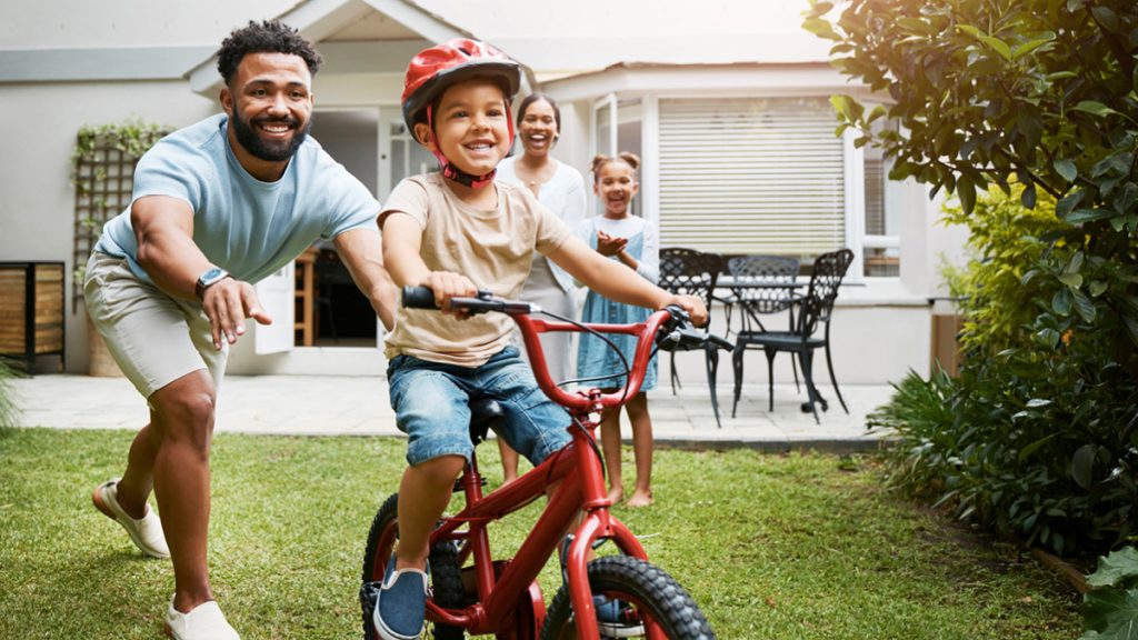 Un père apprend à son fils à faire du vélo dans son jardin