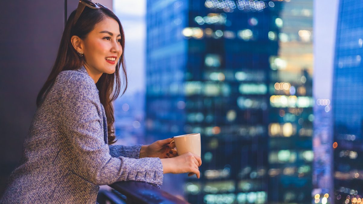 Femme profitant de la vue du soir depuis son balcon tout en regardant la ville