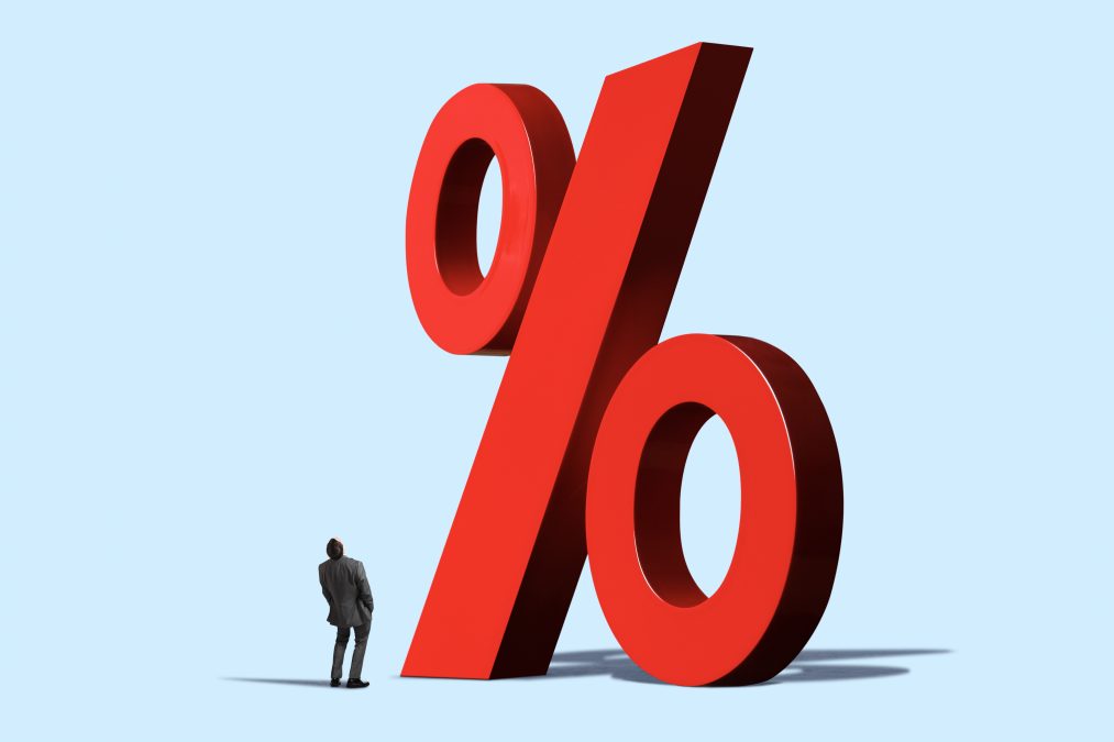 Un homme lève les yeux vers un grand panneau rouge indiquant un pourcentage