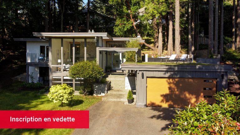 Une maison moderne du milieu du siècle entourée d'arbres pendant la journée