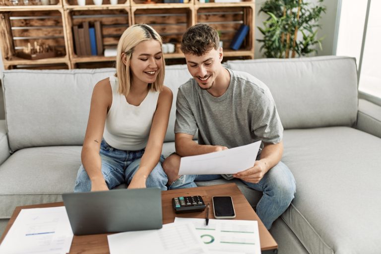 Jeune couple caucasien souriant heureux de contrôler l’économie familiale en utilisant un ordinateur portable à la maison.