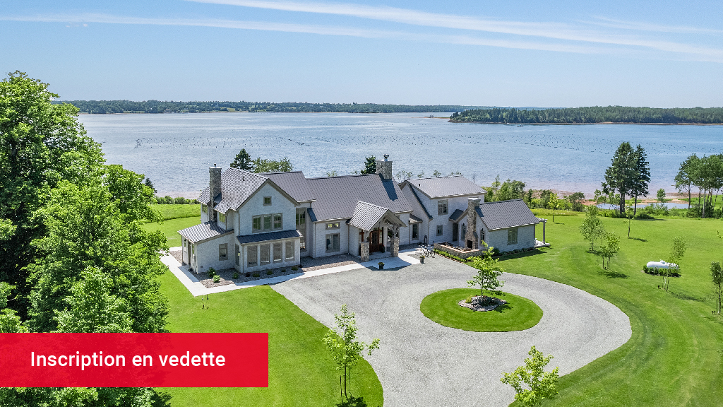 Une grande maison moderne donnant sur le bord de l'eau pendant la journée.