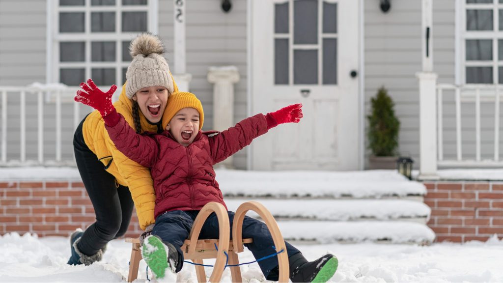 Un jeune frère et une jeune sœur en parkas jouant dans la neige pendant la journée