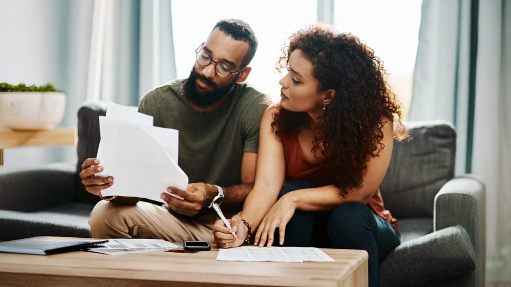 A young couple discussing finances at a living room coffee table