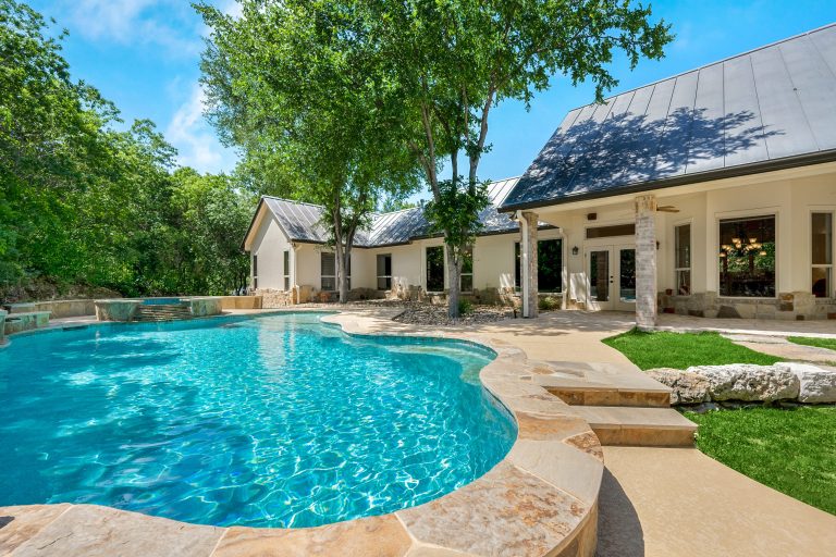 Une piscine creusée bien visible à l'extérieur d'une maison individuelle par une journée ensoleillée.