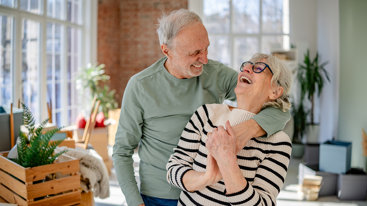 Un couple de personnes âgées rit ensemble dans leur nouvelle maison