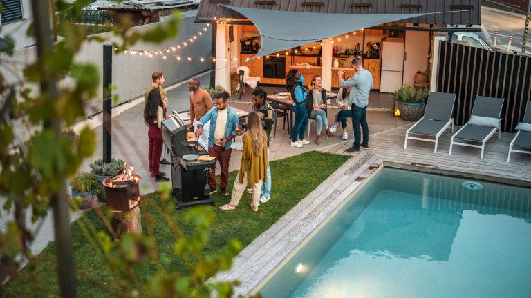 Des adultes réunis dans une cour arrière en soirée pour un souper barbecue
