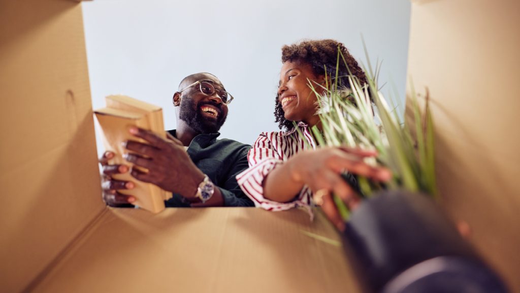 Vue en contre-plongée d'un couple heureux sortant des objets d'un carton de déménagement