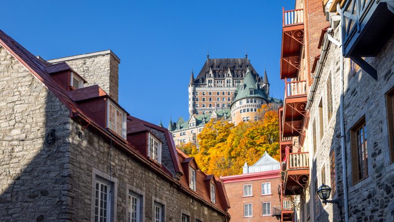 Vue extérieure d'appartements résidentiels à Québec par une journée ensoleillée, avec le Château Frontenac en arrière-plan