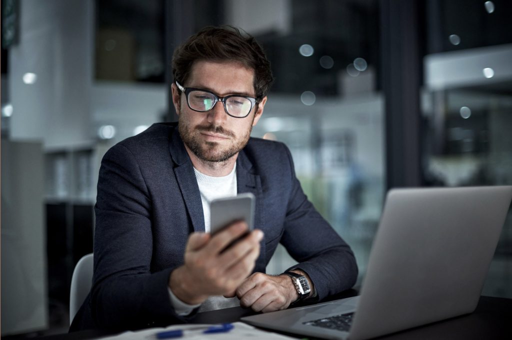 Un homme en costume professionnel regarde son téléphone portable.