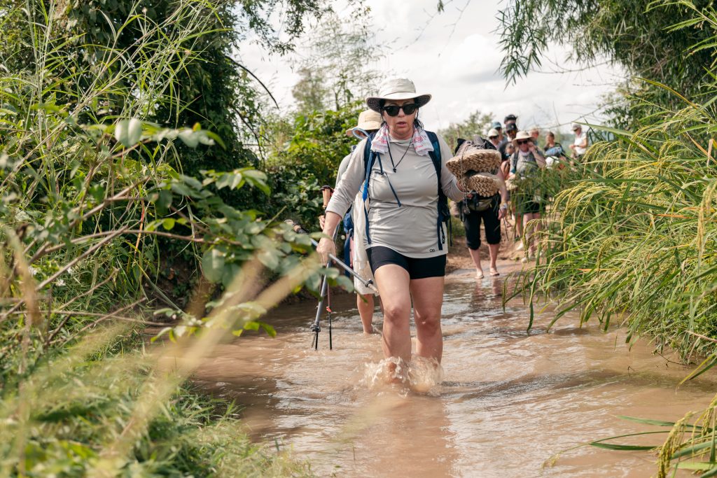 Une femme en tenue de randonnée traverse l'eau dans la jungle cambodgienne