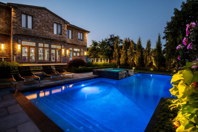 Jardin arrière avec une grande piscine et une terrasse à l'arrière, de nuit