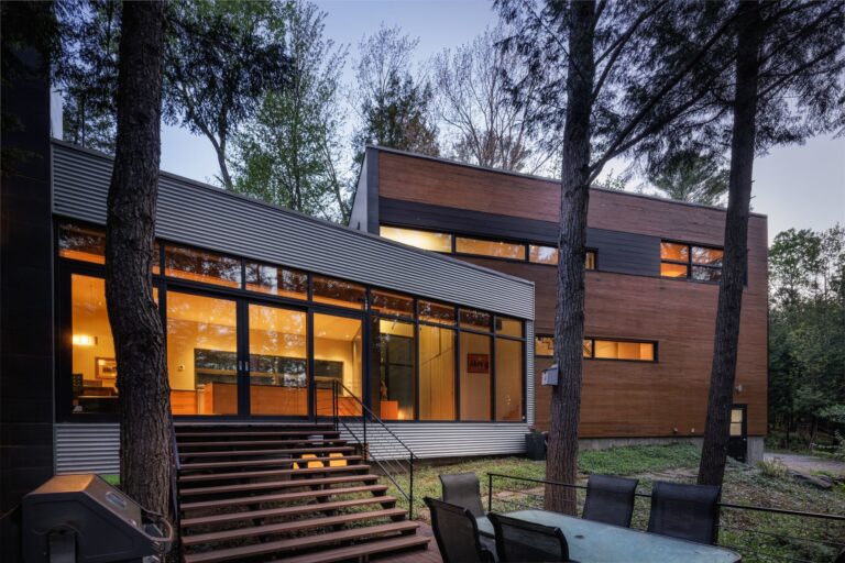 Une maison moderne au crépuscule, dans la forêt.