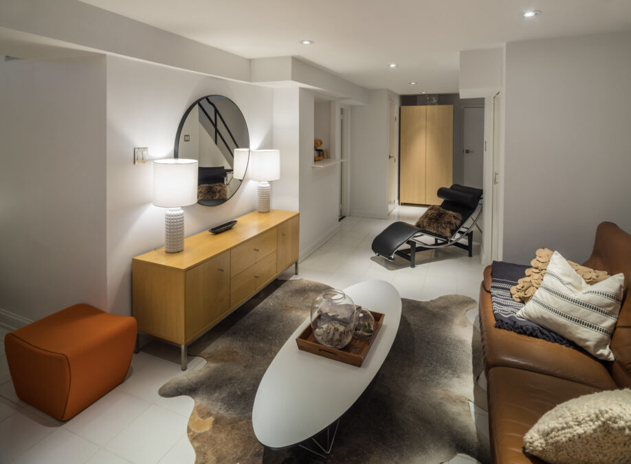 Sous-sol aménagé et lumineux avec un éclairage chaleureux et des meubles confortables