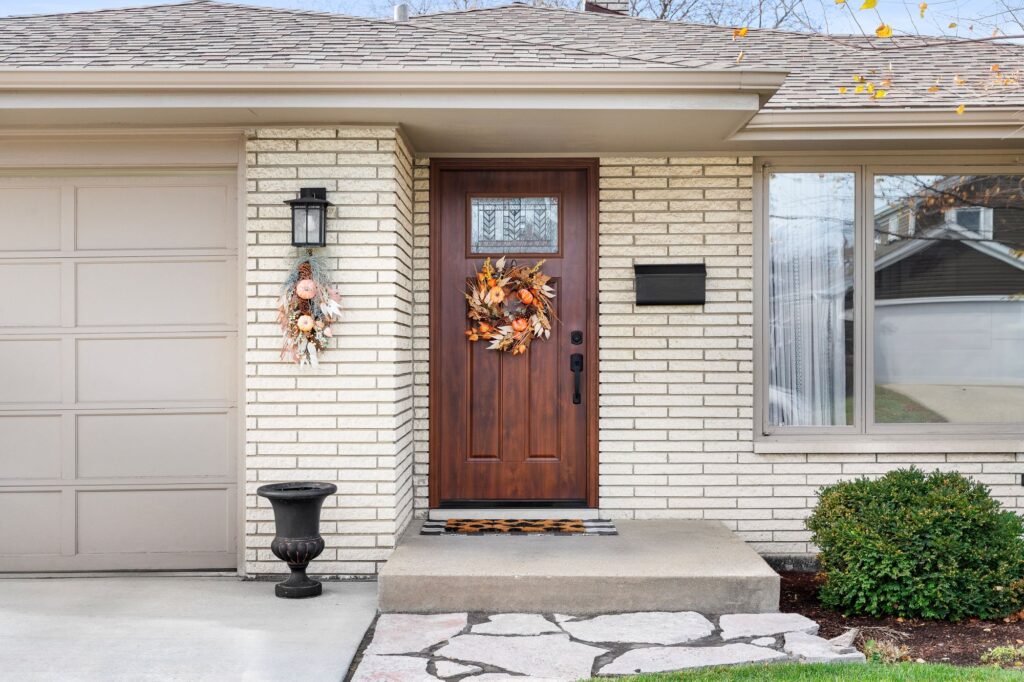 Porte d'entrée en bois ornée d'une couronne sur l'extérieur d'une maison bien entretenue avec une allée propre