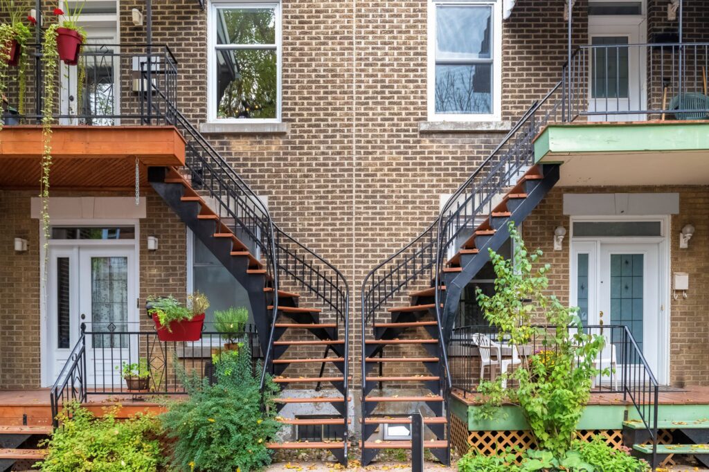 Duplex québécois classique dans une rue résidentielle avec escaliers extérieurs et balcons