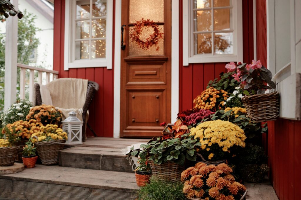 Porte d'entrée rouge d'une maison ornée de plantes à l'automne